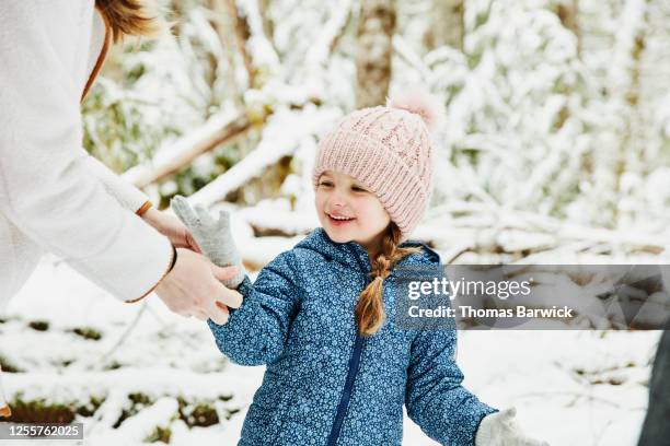 mother helping daughter put on gloves while walking in snow - kid in winter coat stock pictures, royalty-free photos & images