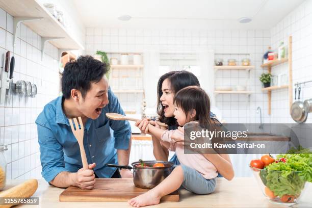 lovely cute asian family making food in kitchen at home. portrait of smiling mother, dad and children standing at cooking counter that food ingredient put on table. - big cook stock pictures, royalty-free photos & images