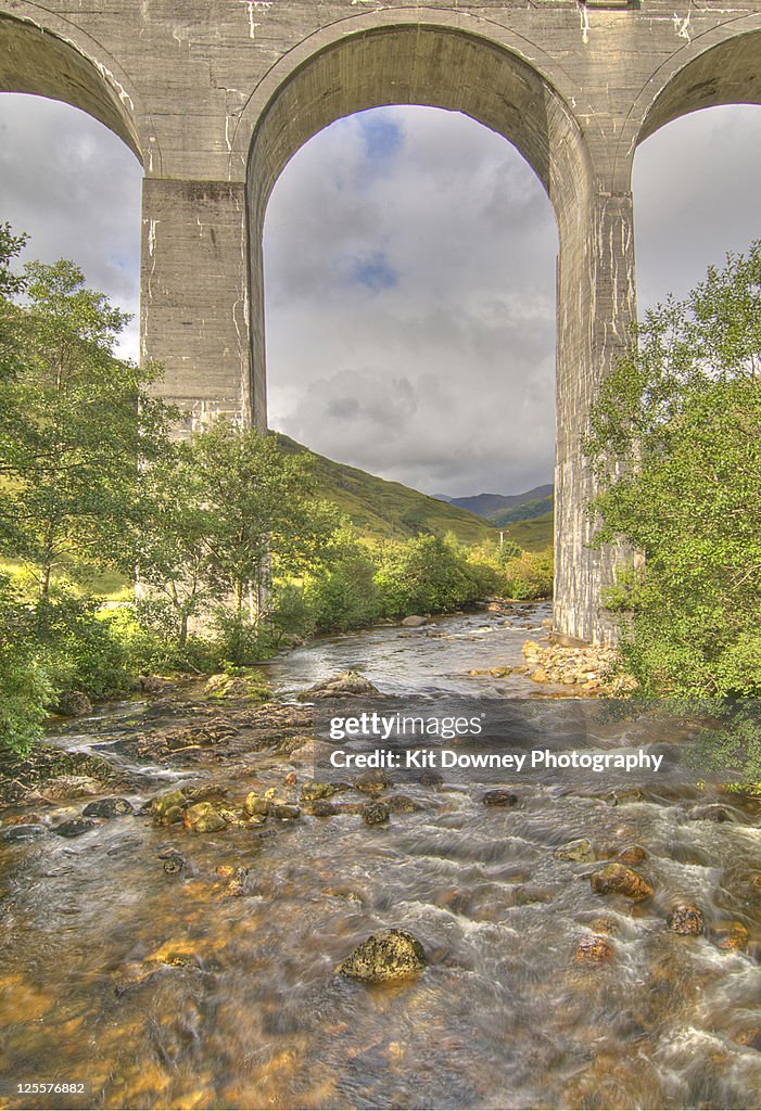 Stream flowing under railway bridge arches