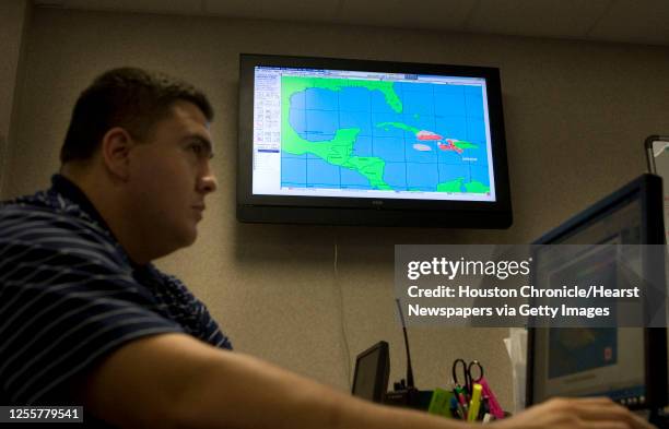 City of Galveston EOC core memeer Jose Sanchez looks at a computor monitor as the HURVAC hurricane monitoring system on the wall displays the...