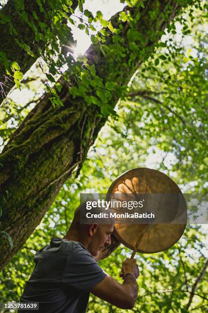 erwachsener mann spielt schamanische trommel - schamane stock-fotos und bilder