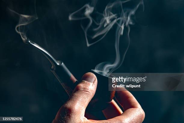 holding a smoking pipe with smoke patterns - tobacconists stock pictures, royalty-free photos & images