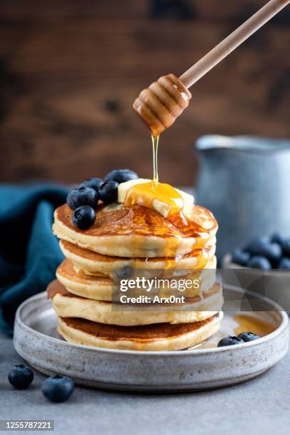 honey pouring on blueberry pancakes - maple syrup pancakes stockfoto's en -beelden