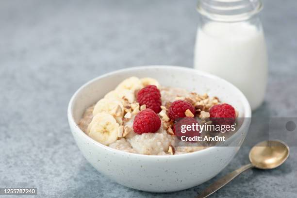 bowl of oatmeal porridge with raspberries and banana slices - muesli stock pictures, royalty-free photos & images