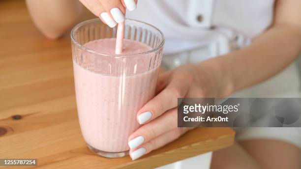 pink strawberry milkshake in female hands - milchshake stock-fotos und bilder