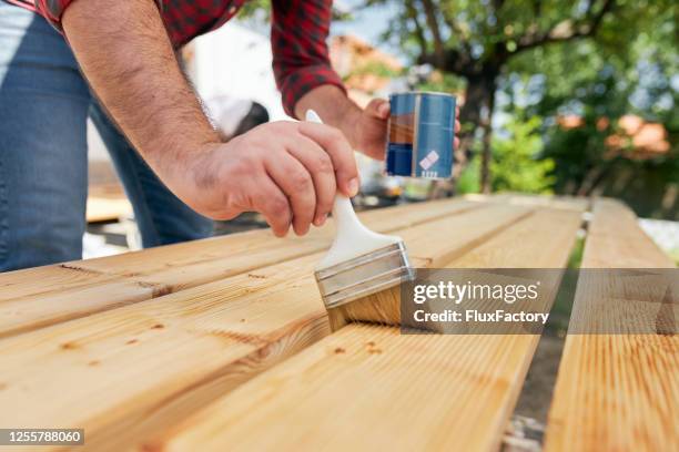 focused mid adult carpenter varnish a wooden board with protective oil - timber yard stock pictures, royalty-free photos & images