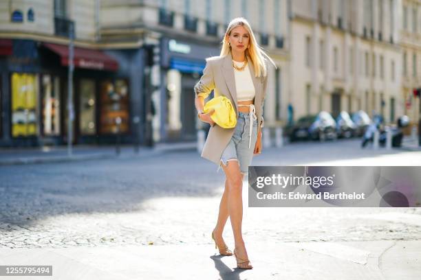 Leonie Hanne wears golden earrings, a golden necklace, a white cropped top from Orseund Iris, a gray oversized long blazer jacket from Frankie Shop,...