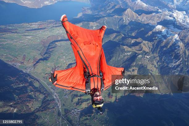 wingsuit flier soars over swiss alps - wing suit stock pictures, royalty-free photos & images