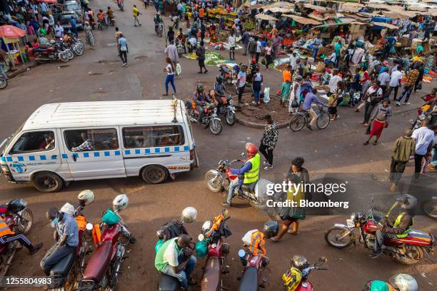 Taxi van makes its way along a road through a busy market area in downtown Kampala, Uganda, on Wednesday, May 17, 2023. Uganda estimates that it will...