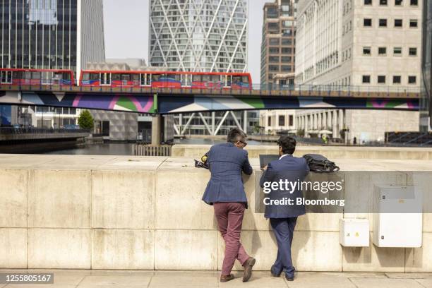 Workers near a passing Docklands Light Railway train in the Canary Wharf business district in London, UK, on Thursday, May 18, 2023. A series of...