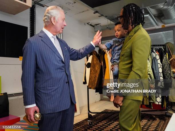 Britain's King Charles III gives a hi-five to Idris the son of founder and creative director of LABRUM London Foday Dumbuya and winner of the Queen...