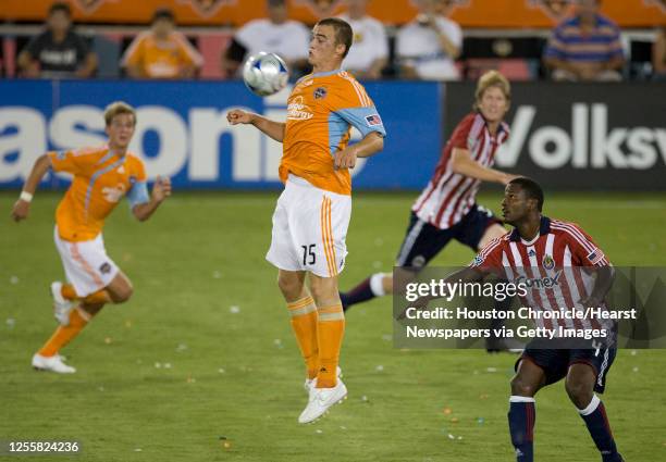 The Houston Dynamo's Cam Weaver moves the ball as teammate Stuart Holden and Chivas USA's Shavar Thomas look on during the second half of MLS game...