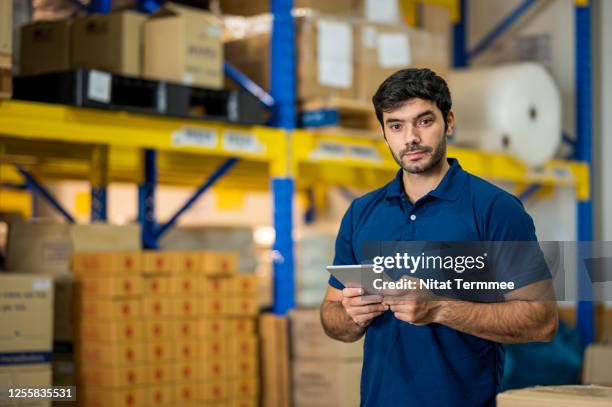 warehouse worker using digital tablet for taking inventory in distribution warehouse. supply chain, warehouse management. - polohemd stock-fotos und bilder