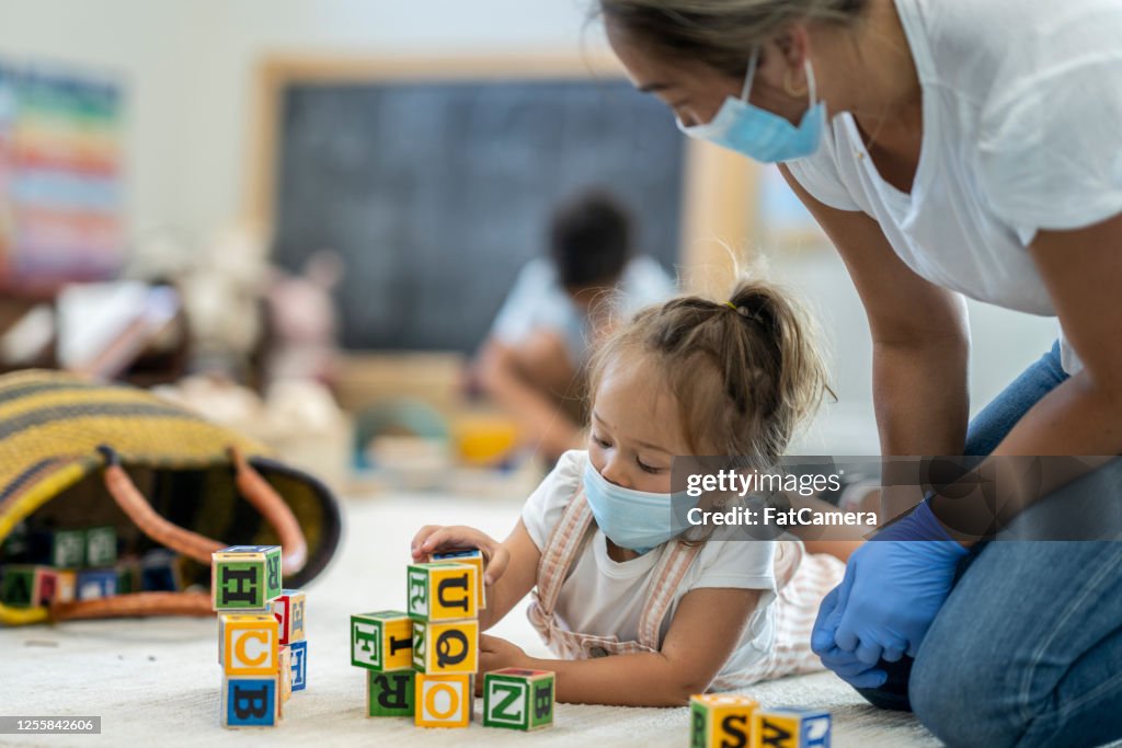 Young girl playing at daycare wearing a protective mask