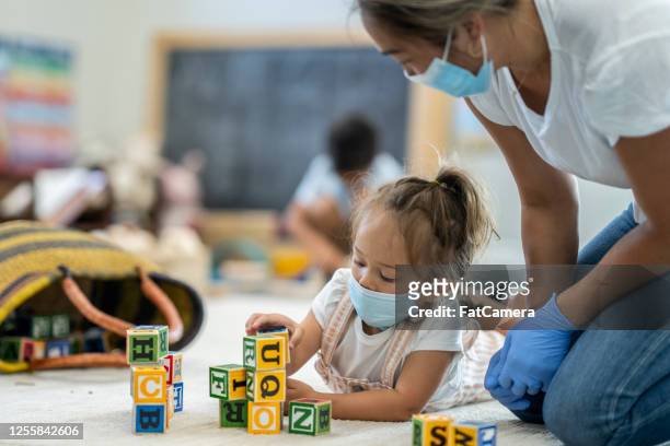 young girl playing at daycare wearing a protective mask - preschool stock pictures, royalty-free photos & images