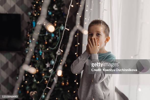 beautiful little boy, lying down on the floor, looking at candles, making wishes for christmas - face down stock-fotos und bilder