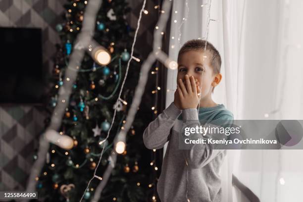 beautiful little boy, lying down on the floor, looking at candles, making wishes for christmas - surprise face kid - fotografias e filmes do acervo