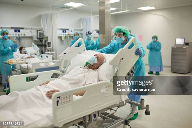 trabajador de la salud que se muda a un paciente covid-19 en la cama del hospital - infectious disease fotografías e imágenes de stock