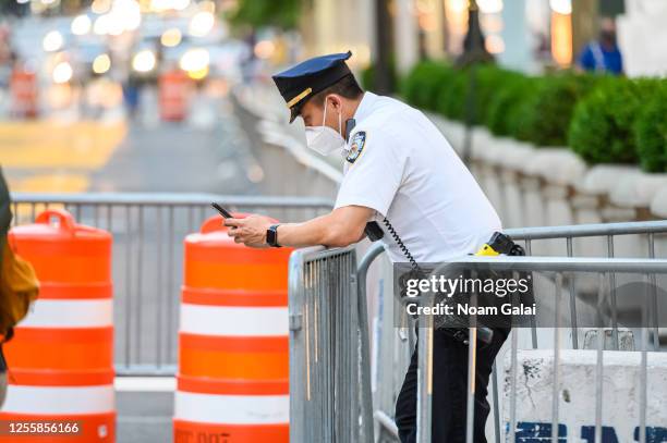 An NYPD officer wears a protective face mask outside of Trump Tower on Fifth Avenue as New York City moves into Phase 3 of re-opening following...