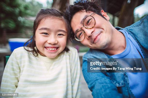 Young handsome dad taking selfies joyfully with her lovely daughter while enjoying barbecue picnic in country park