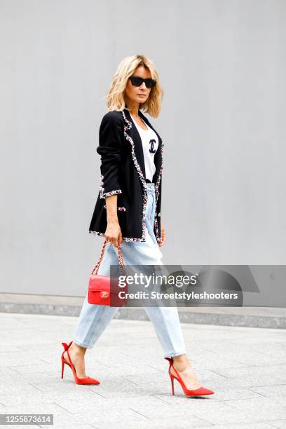 Influencer Gitta Banko, wearing a white tank top by Chanel, a black blazer with multicolored stones by Chanel, a ballon jeans by Magda Pytrum, a red...