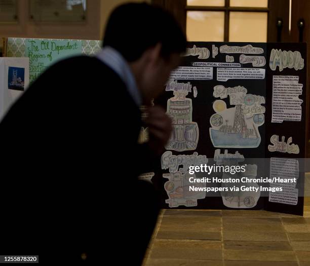 Judge looks over entrants in the poster board contest during the World Affairs Council Student Energy Summit at the Boy Scouts of America Sam Houston...