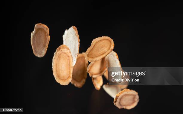 american ginseng slices flying in mid air with black background - ginseng stockfoto's en -beelden