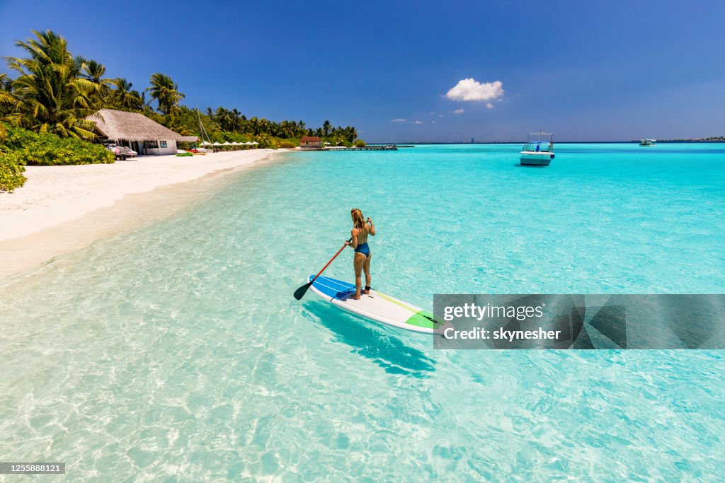 Vista trasera de las mujeres despreocupadas paddleboard en el día de verano en el mar.