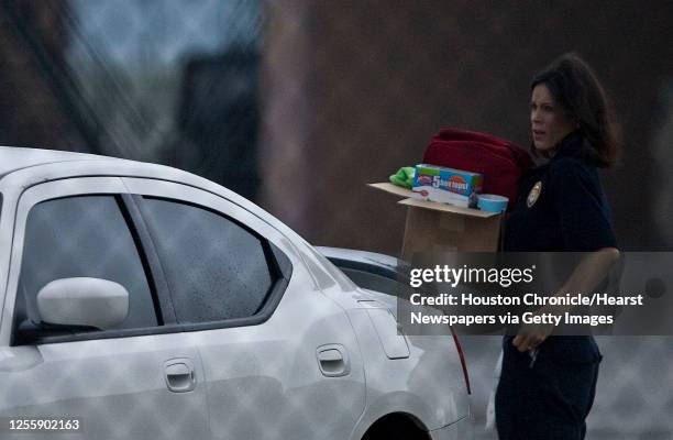 The Houston Fire Department's Jane Draycott carries a box of personal belongings Monday, April 19 in Houston, as she return to work at fire station...