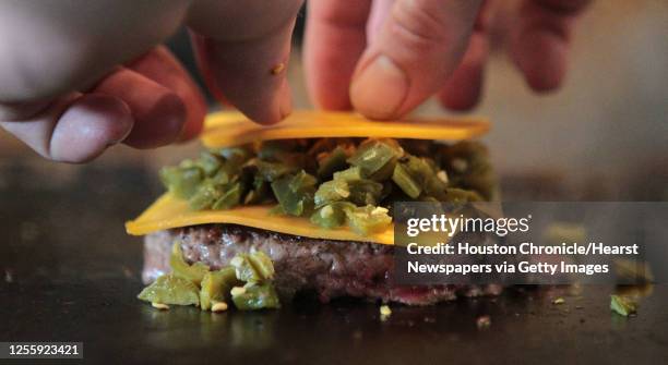 Brandon Fisch prepares a Houston burger which includes Onion Bacon Jam, Fancy Lawnmower Ale Mustard, bread and butter jalapenos and cheddar cheese at...