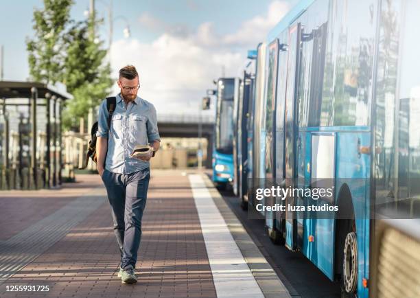 man walking and reading a book at the bus stop - bus gothenburg stock pictures, royalty-free photos & images