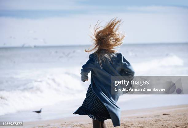 woman with long hair running towards the ocean - long hair back stock pictures, royalty-free photos & images