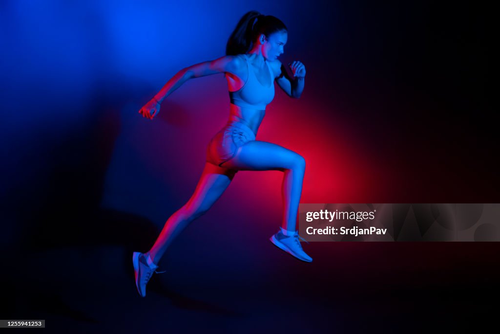 Studio shot of a young sportswoman performing running jump