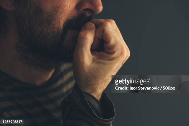 side view close up of nervous man biting fingernails, novi sad, serbia - middle finger stock-fotos und bilder