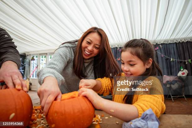 mother and daughter carving pumpkins - frieze stock pictures, royalty-free photos & images