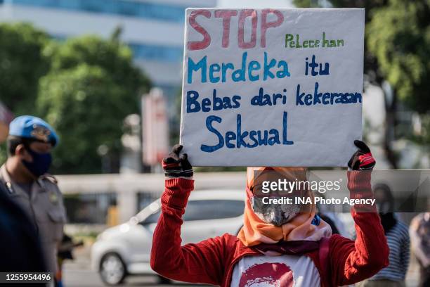 Indonesian woman activist wearing a face mask holds a placard, during a demonstration in front at the People's Representative Council of Indonesia to...