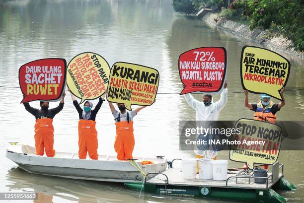 Indonesian environment activists from the Ecology and Wetland Conservation Institute seen holding placards on a boat in Kalimas rivers, Surabaya,...