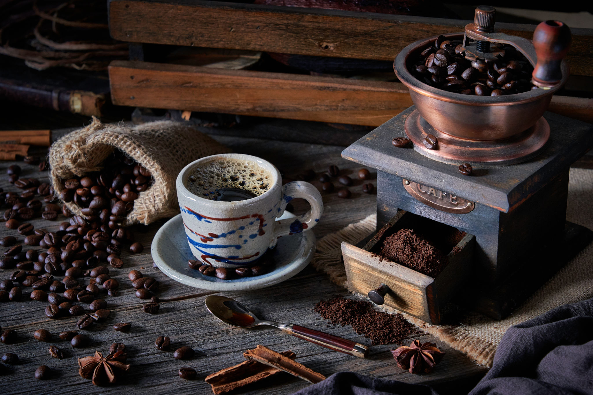 Espresso coffee cup and grinder on vintage table and roasted coffee beans in a burlap Espresso coffee cup and grinder on vintage table and roasted coffee beans in a burlap