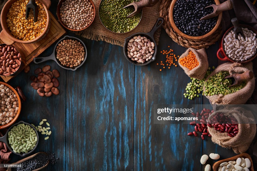 Top view low key image of a large variety of dry beans. Shot from above on rustic wooden blue table making a frame