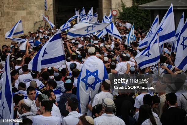 Demonstrators waving Israeli flags gather outside the Damascus Gate of the Old City of Jerusalem during the annual 'flag march' to mark 'Jerusalem...