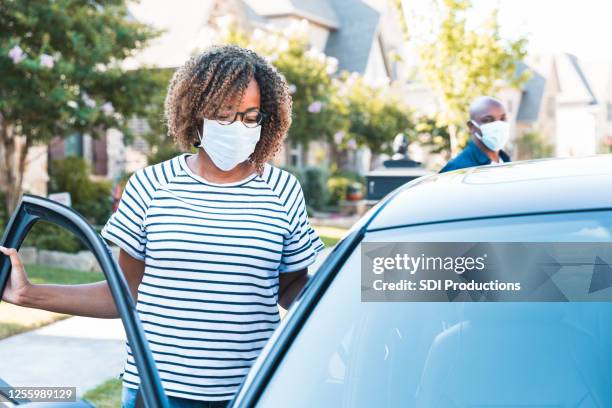 during covid-19, couple wears masks while getting in car - car isolated doors open stock pictures, royalty-free photos & images