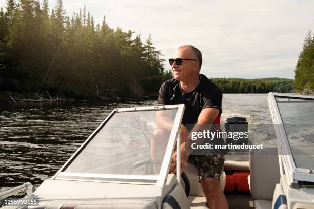 50 + hombre conduciendo barco pequeño en un lago. - speedboat fotografías e imágenes de stock