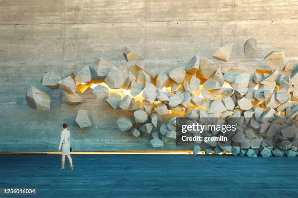 empresaria de pie frente a la pared de ruptura - realismo conceptual fotografías e imágenes de stock