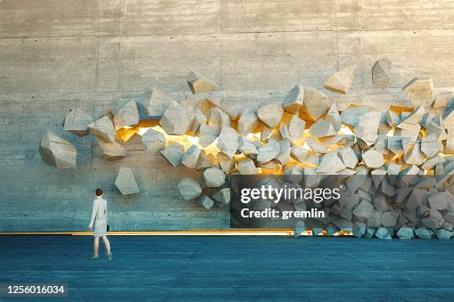 Businesswoman standing in front of breaking wall Businesswoman standing in front of breaking wall
