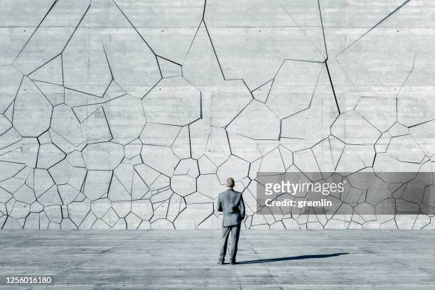 hombre de negocios de pie frente a la pared de ruptura - valla límite fotografías e imágenes de stock