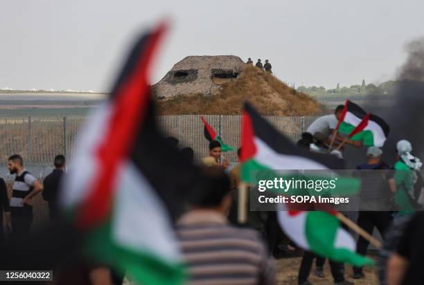 Israeli soldiers are seen on a fortified position as protesters gather during a Palestinian 'flag march' along the border with Israel east of Gaza...