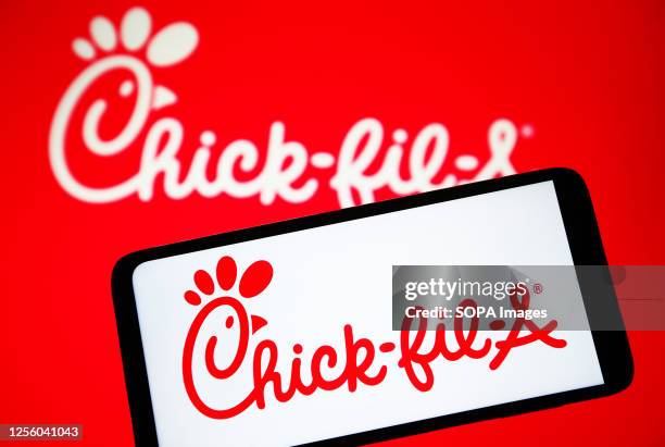 In this photo illustration, Chick-fil-A logo is seen on a smartphone and on a pc screen.