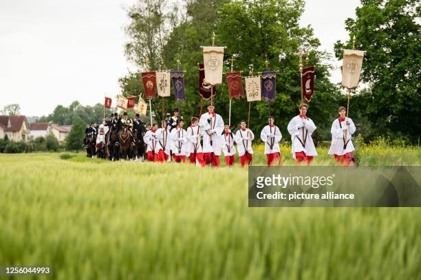 May 2023, Baden-Württemberg, Weingarten: Altar boys and blood riders march in procession along a field. The Blood Ride is Europe's largest equestrian...