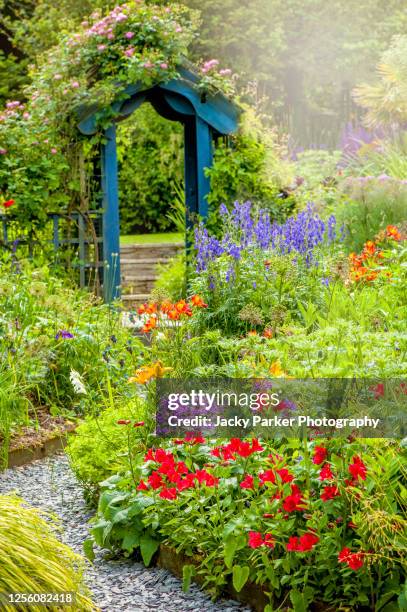 beautiful english cottage, summer garden with blue wooden archway, in soft sunshine - casita de campo fotografías e imágenes de stock