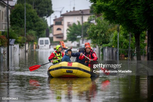 Firefighters rescuers evacuate residents in a dinghy across a flooded street after heavy rains caused flooding across Italy's northern Emilia Romagna...